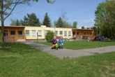 Mateřská škola Sluníčko – pohled na zahradu mateřské školy s kolotočem, houpačkou, v pozadí budova mateřské školy Školní 1804  